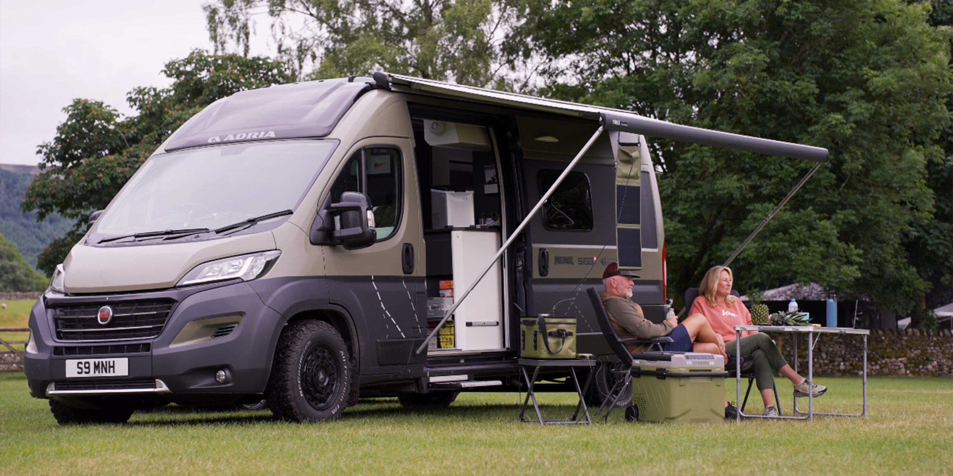 Image of a man and woman sat outside of a motorhome with their Softcool 25 and TF-XTREME 50 both in camo green