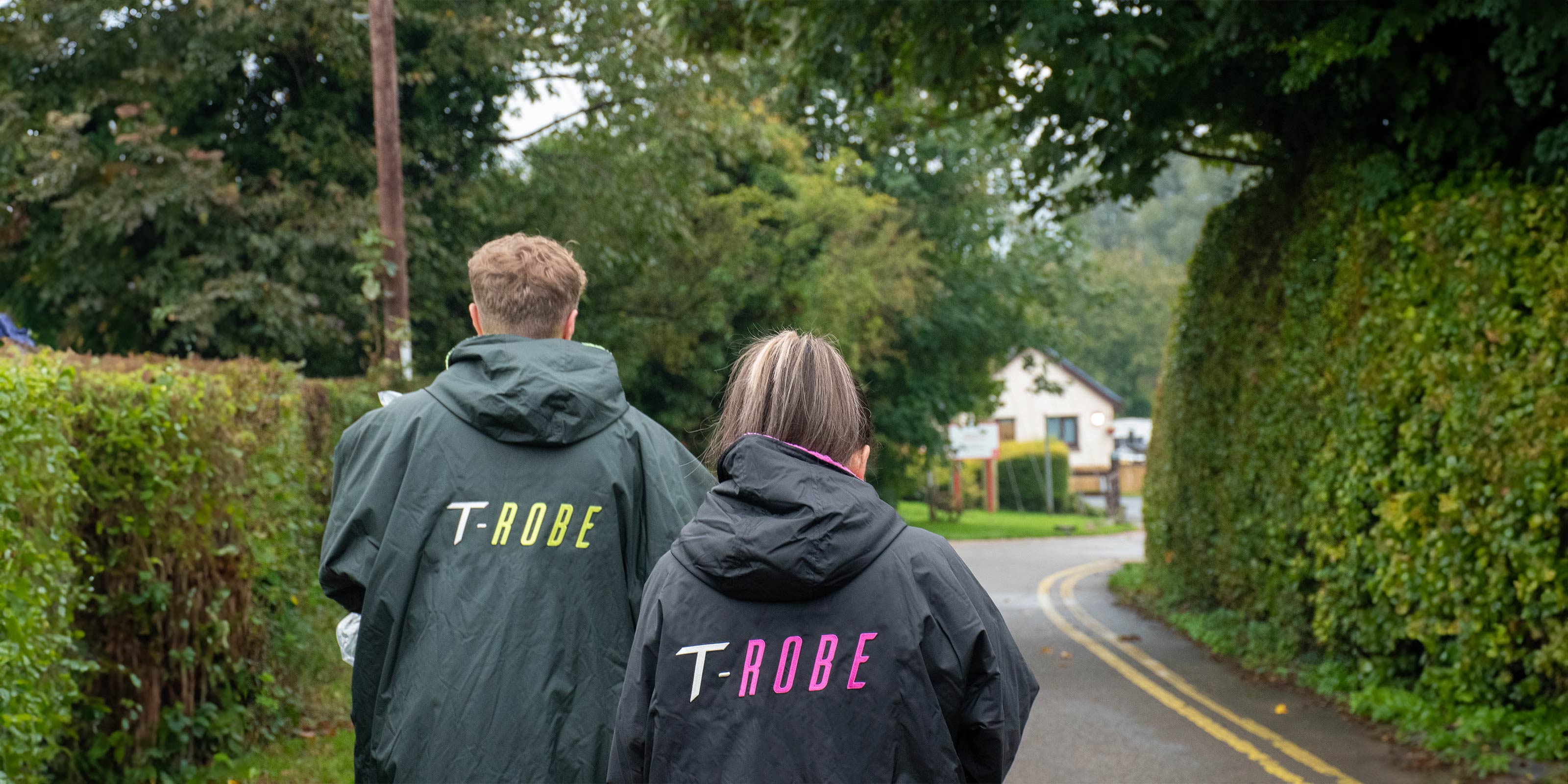 Image of a man and woman wearing T-Robes walking through a campsite