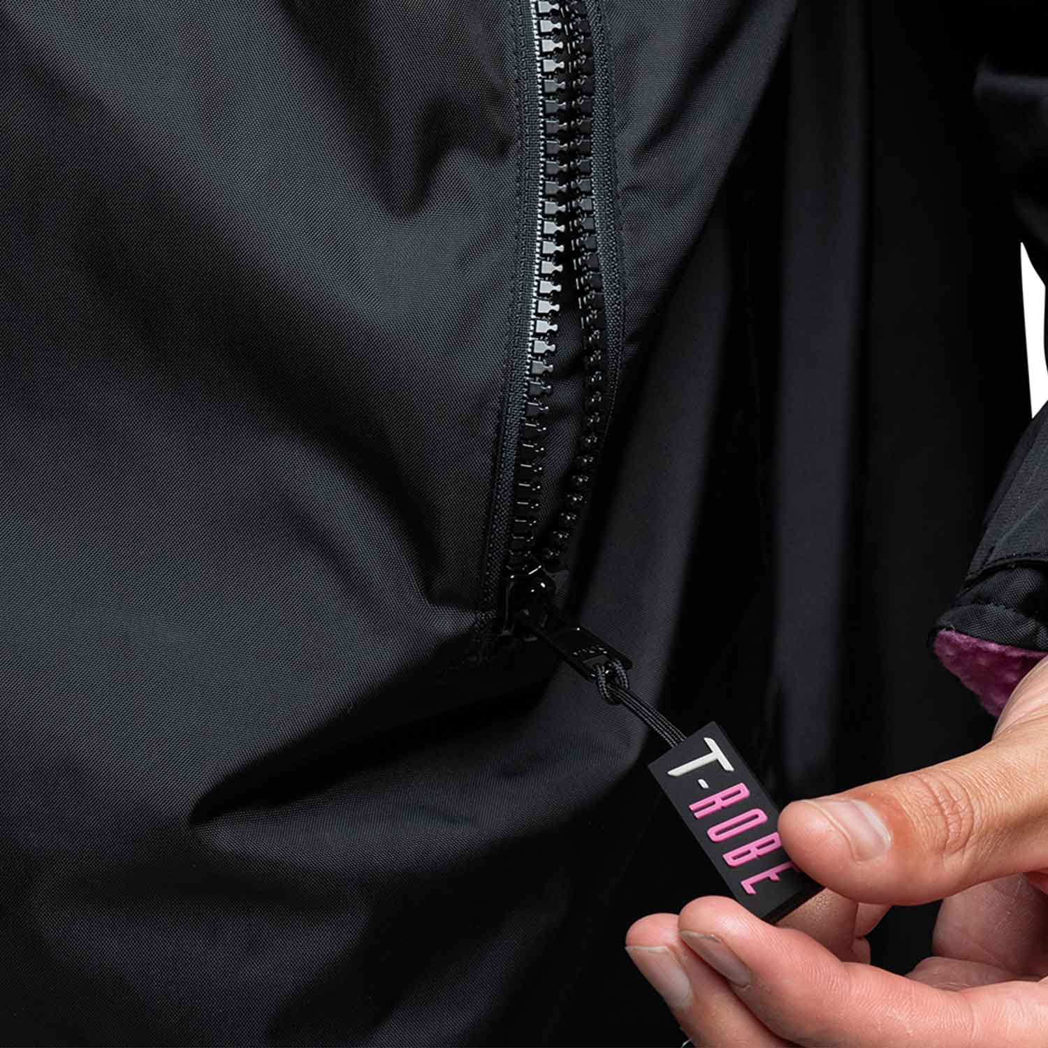 Close up image of branded zippers on the pockets for the Black and pink T-Robe 