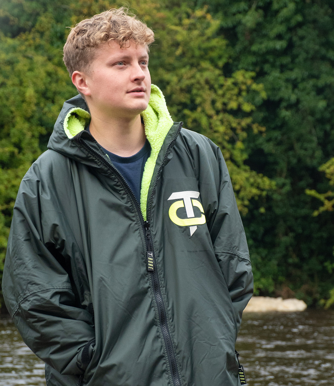 Image of a man wearing a deep green / lime T-Robe out in the woods