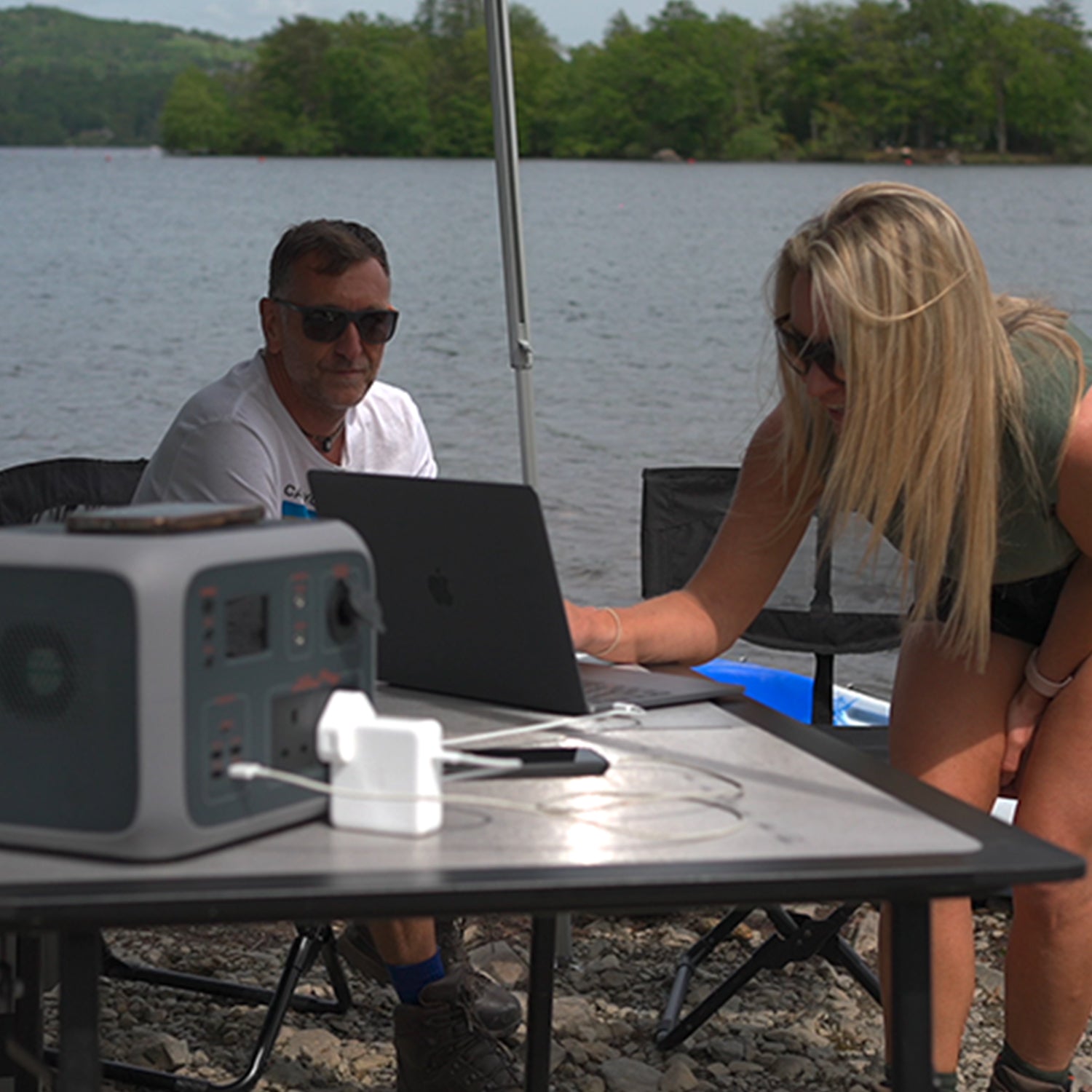 TP500 charging two phones and a laptop via different methods outdoors, wireless, AC and USB-A 